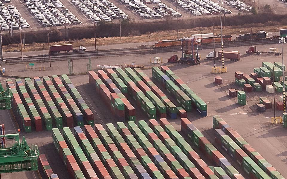 Aerial view of stacked shipping containers, trucks and freight trains at a port