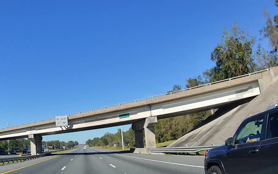 Highway seen from a vehicle camera with detection boxes around a car and a road sign